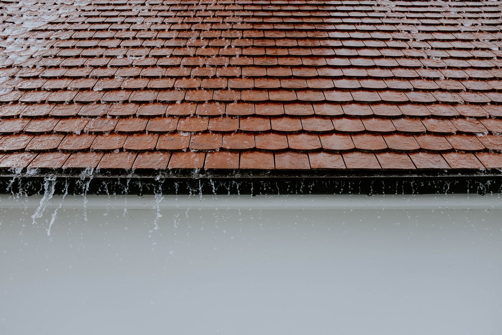 A house roofline and its gutters on a grey rainy day
