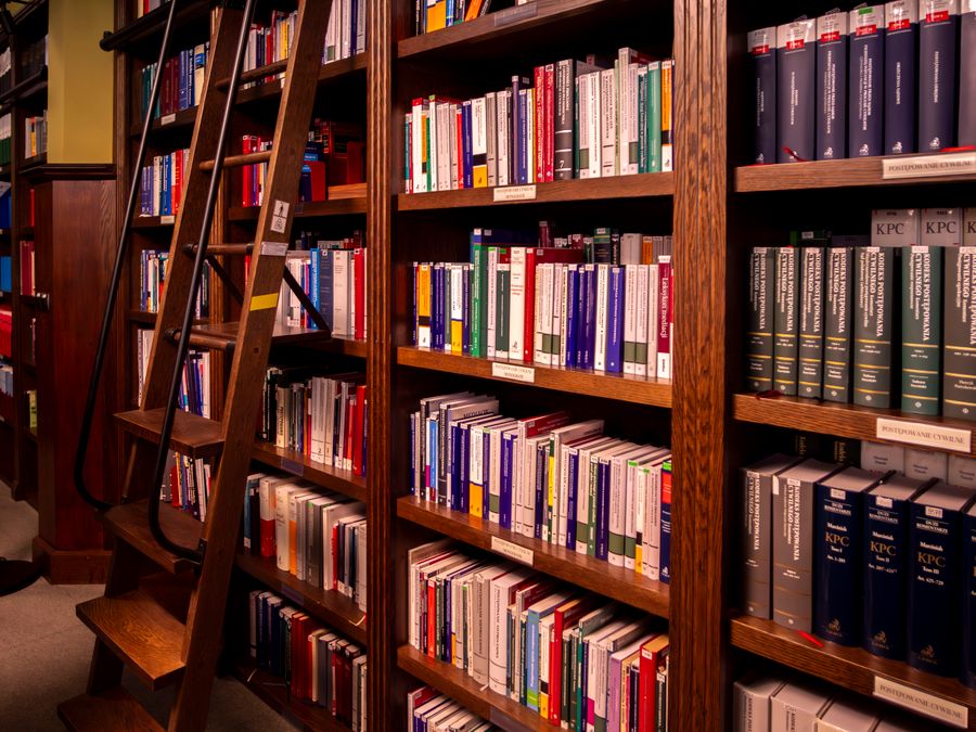Library shelves of bound volumes beside a wooden ladder
