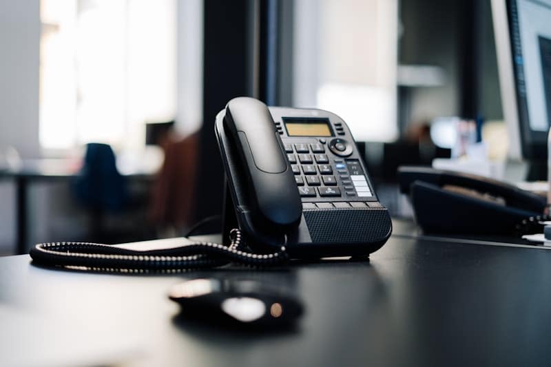 Black IP desk phone on a dark office desk