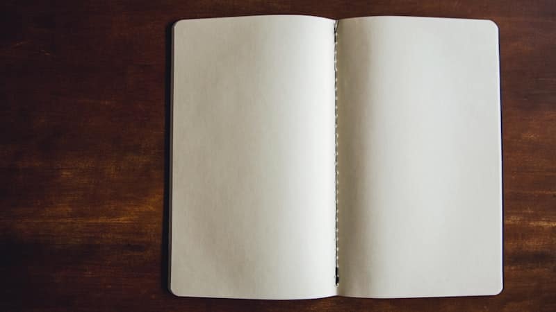 Open blank notebook lying on a dark wooden desk