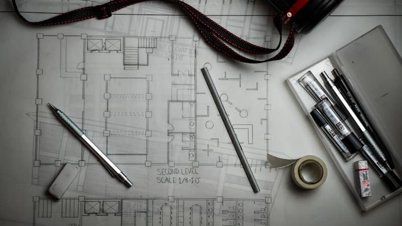 Architectural floor plans with drafting pens and a ruler
