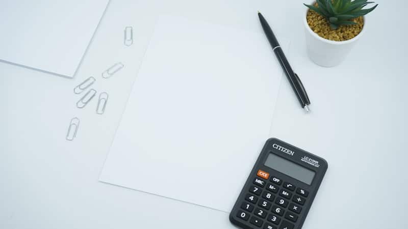 Calculator, pen and blank paper on a white desk