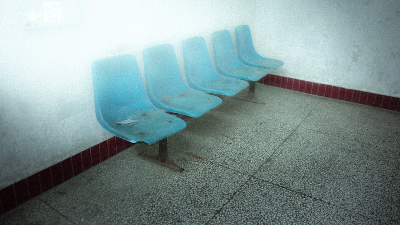 Row of empty blue moulded chairs in a waiting area
