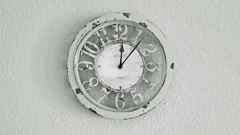 Weathered analog wall clock mounted on a plain white wall