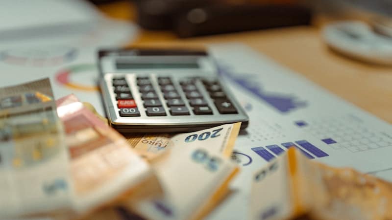 Calculator resting on banknotes and printed charts