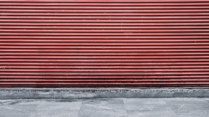Closed red roller shutter over a shopfront