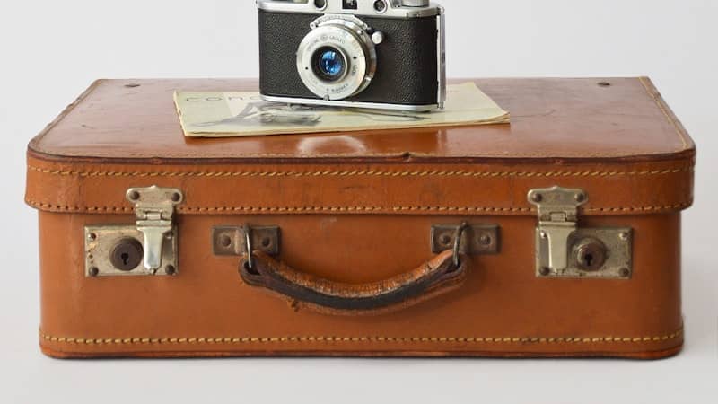 Vintage camera resting on a brown leather suitcase